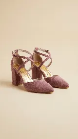 Zapato de tacón alto con diseño de punta fina y escote en V. Presenta tiras cruzadas en el empeine con cierre de hebilla ajustable en el tobillo y taco cuadrado. Confeccionado en gamuza con interior y plantilla de cuero.