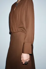 Vestido midi de viscosa color marrón, con escote cruzado en pico, manga larga con puños y falda evasé.