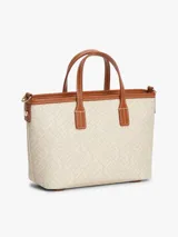 Cartera tote Tommy Hilfiger modelo TH Monoplay, color beige con estampado integral del monograma TH en relieve, asas superiores y correa bandolera extraíble de cuero sintético marrón. Cuenta con cierre de cremallera e insignia metálica del monograma en el frente.