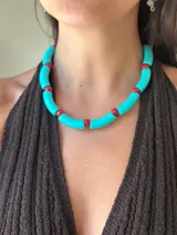 Collar corto tipo gargantilla compuesto por cuentas tubulares acrílicas de color turquesa y cuentas pequeñas de cristal checo de color rojo.