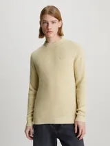 Sweater color crema de algodón con textura de canalé, cuello redondo e insignia de Calvin Klein Jeans bordada en el pecho.