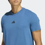 Remera de entrenamiento Adidas con tecnología AEROREADY para absorción de humedad. Presenta cuello redondo, ajuste ceñido, cortes en los dobladillos laterales y dobladillo trasero ligeramente más largo. Incluye el logo de la marca estampado en el centro del pecho.