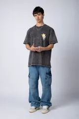 Remera de algodón con efecto acid wash en color gris oscuro. Presenta un diseño estampado en el pecho con una estrella amarilla y un personaje animado, y un corte semi-oversize.
