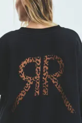 Buzo negro oversize de frisa esmerilada con cuello alto, hombros caídos, bolsillos laterales y estampa en la espalda con el logo de la marca en animal print.