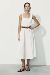 Vestido midi de color blanco con escote cuadrado y tirantes finos. Presenta un diseño acampanado con pliegues y un cinturón de cuero sintético en color tostado con hebilla metálica dorada.