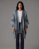 Ruana de lana con diseño de rayas verticales en tonos azul y gris, con terminación de flecos en el ruedo.