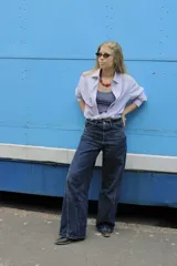 Pantalón jean azul oscuro, de corte wide leg y tiro medio. Presenta detalles de costuras diagonales en la parte superior.