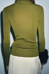 Jersey de cuello alto y manga larga, confeccionado en tejido de lana extrafina de textura suave y acabado liso.