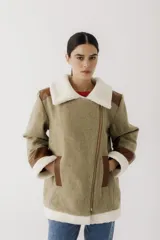 Gamulán de paño en color beige jaspeado con detalles en cuero sintético marrón y forro de corderito sintético blanco. Presenta cierre frontal cruzado, cuello solapa, bolsillos laterales y puños con vuelta.