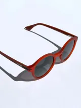 Lentes de sol Osten modelo Niza con armazón redondo de color rojo mate y cristales oscuros polarizados con protección UV 400.