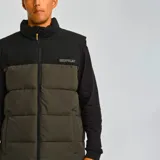 Chaleco acolchado Caterpillar con diseño bicolor en negro y verde oliva. Presenta cierre frontal completo, cuello alto, bolsillos laterales con cierre y logo de la marca estampado en el pecho.