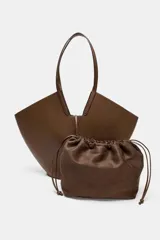 Bolso de hombro estilo capazo, color marrón, con doble asa de hombro y cuerpo con pespuntes. Presenta un cierre mediante pasador con clip metálico y una bolsa interior extraíble con cierre fruncido.
