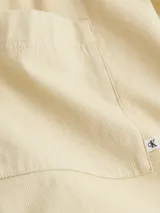 Bermuda color beige de algodón regenerativo, con cintura elástica, bolsillos laterales y traseros.