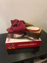Sandalias negras de cuero sintético con tacón bloque y detalle de moños con pespuntes blancos en el empeine.