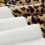 Campera tipo polar con cierre frontal, diseño combinado con estampado animal print en la parte superior y tejido de peluche blanco en la parte inferior. Cuenta con capucha con cordones ajustables y dos bolsillos frontales.