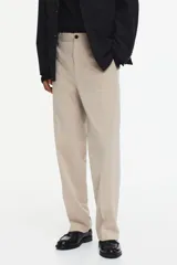 Pantalón de vestir color beige, de corte relajado, con bolsillos laterales y traseros, y raya marcada en las piernas.