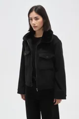 Chaqueta negra de corte holgado con cierre frontal, cuello camisero con detalle de corderito y bolsillos frontales con solapa y botones.