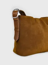 Morral de cuero descarne color marrón con textura suave, diseño estructurado con costura central vertical y detalle de logotipo grabado en relieve en la parte inferior. Cuenta con correa ajustable para el hombro y herrajes metálicos.