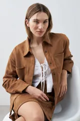 Chaqueta color tostado simil gamuza con cuello clásico, cierre con botones a presión, bolsillos de parche en el pecho y corte recto.
