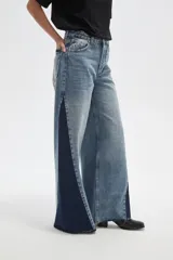 Pantalon de jean de corte ancho con diseño color block, combinando paneles de denim lavado claro en el centro y denim azul oscuro en los laterales. Presenta tiro medio y terminaciones deshilachadas en el ruedo.