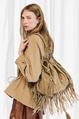 Cartera bandolera de cuero vacuno color tostado, con diseño de flecos largos y detalles de costuras artesanales y tientos decorativos.