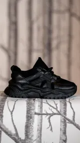 Zapatillas urbanas negras con suela chunky y cordones.