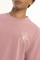 Remera marrón de corte holgado con estampado de una flor en el pecho.