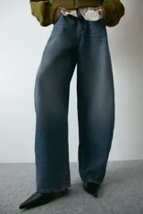 Jean de tiro alto y corte baggy, confeccionado en denim de algodón rígido en tono azul medio con efecto deslavado. Presenta diseño de cinco bolsillos, trabillas para cinto y cierre frontal con botón y cremallera.