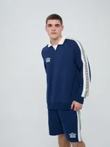 Buzo deportivo Umbro modelo Mixtape, color negro con cuello polo blanco y franjas blancas en las mangas con logo de la marca. Cuenta con puños y cintura elastizados.