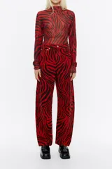 Pantalón vaquero de corte barrel, tiro medio, largo tobillero y estampado animal print de cebra en rojo y negro.