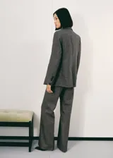 Blazer de corte recto confeccionado en tejido de mezcla de lana jaspeada. Presenta cuello con solapas de muesca, cierre frontal con botones, mangas largas con puños abotonados, dos bolsillos de parche frontales y abertura posterior en el bajo. Incluye forro interior.