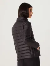 Campera puffer color crudo, con cuello alto y cierre frontal. Tiene bolsillos laterales y diseño matelassé horizontal.