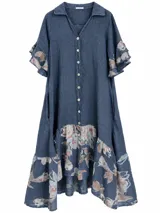 Vestido midi azul jean con cierre frontal de botones, cuello camisero y mangas cortas con volados. Presenta detalles de tela estampada con diseño floral en las mangas, el ruedo y la parte inferior.