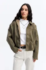 Campera de gamuza sintética color verde oliva, con silueta amplia, hombros caídos y cierre frontal. Presenta un diseño estructurado con volumen en mangas y cuerpo.