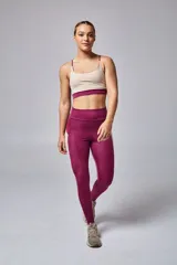 Top deportivo color beige con contorno inferior y tiras cruzadas en la espalda color borgoña. Cuenta con almohadillas removibles.