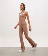 Pantalón deportivo de tiro alto con corte flare, confeccionado en microfibra elástica. Presenta un diseño ajustado en caderas y muslos con una apertura acampanada desde la rodilla y detalle de tajo lateral en el ruedo.