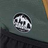 Mochila de senderismo Caterpillar modelo Himalayas Hiking Bac, color verde eucalipto, confeccionada en tejido ripstop de poliéster hexagonal antidesgarro. Presenta cordón elástico delantero de color naranja para almacenamiento adicional, ribetes en color marrón claro y bolsillo lateral de malla negra. Incluye parche de Hypalon en la parte delantera y etiqueta tejida con el logo "Urban Mountain".