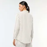 Camisa de lino mezclado color blanco con rayas verticales oscuras, cuello camisero, manga larga y cierre frontal con botones.