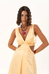 Vestido largo de tela sedosa color durazno, con escote en V, aberturas laterales en la cintura (cut-out) y tajos laterales en la falda. Posee espalda regulable con lazo y elástico.