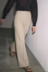Jeans de tiro alto y pierna ancha de Zara, confeccionados en mezcla de algodón color beige. Presentan cintura con trabillas, bolsillos de parche en la espalda, costuras frontales marcadas y cierre delantero con cremallera, botón y gancho metálico.