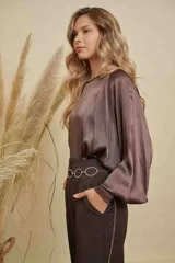 Blusa de satén color marrón chocolate, con cuello a la base, mangas anchas y puños elásticos con detalle bordado.