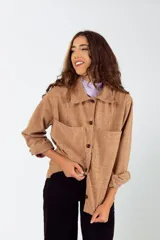 Camisa color mostaza de paño, corte oversize, con cuello clásico, cierre frontal con botones, mangas largas con puños abotonados y dos bolsillos de parche en el pecho.