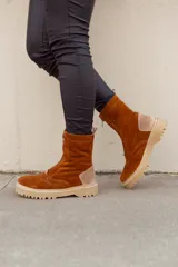 Bota de caña media color marrón óxido, confeccionada en cuero gamuzado. Presenta cierre frontal con cremallera, suela track color beige y detalle de pieza de cuero en la parte trasera del tobillo.