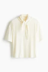 Top de punto suave de algodón color beige, con cuello tipo fular integrado, hombros caídos y mangas cortas.