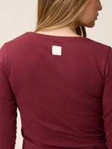 Remera de manga larga color gris, con cuello en V y logo bordado de un pájaro en el pecho.