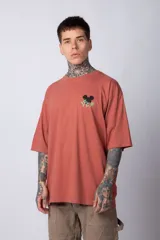 Remera negra de algodón de corte oversize, con mangas cortas y cuello redondo. Estampado pequeño en el frente y diseño grande en la espalda con Mickey Mouse y caracteres orientales en tonos rojizos.