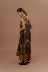 Vestido largo verde militar con estampa tropical de palmeras en tonos amarillos, escote en V y detalles en marrón.