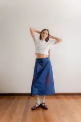 Falda midi de corte recto confeccionada en popelina de algodón, con diseño estampado floral en tonos azules y rojizos sobre fondo azul oscuro. Presenta un diseño con pinzas en la cintura y cierre frontal.