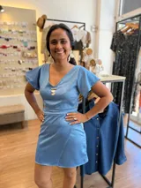 Conjunto de dos piezas color celeste satinado, compuesto por un top de escote en V con mangas cortas tipo volado y una falda corta tipo pareo con detalle de solapa cruzada.