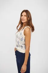 Chaleco de tejido de punto color crema con diseño de rombos en azul claro, escote en V y sin mangas.